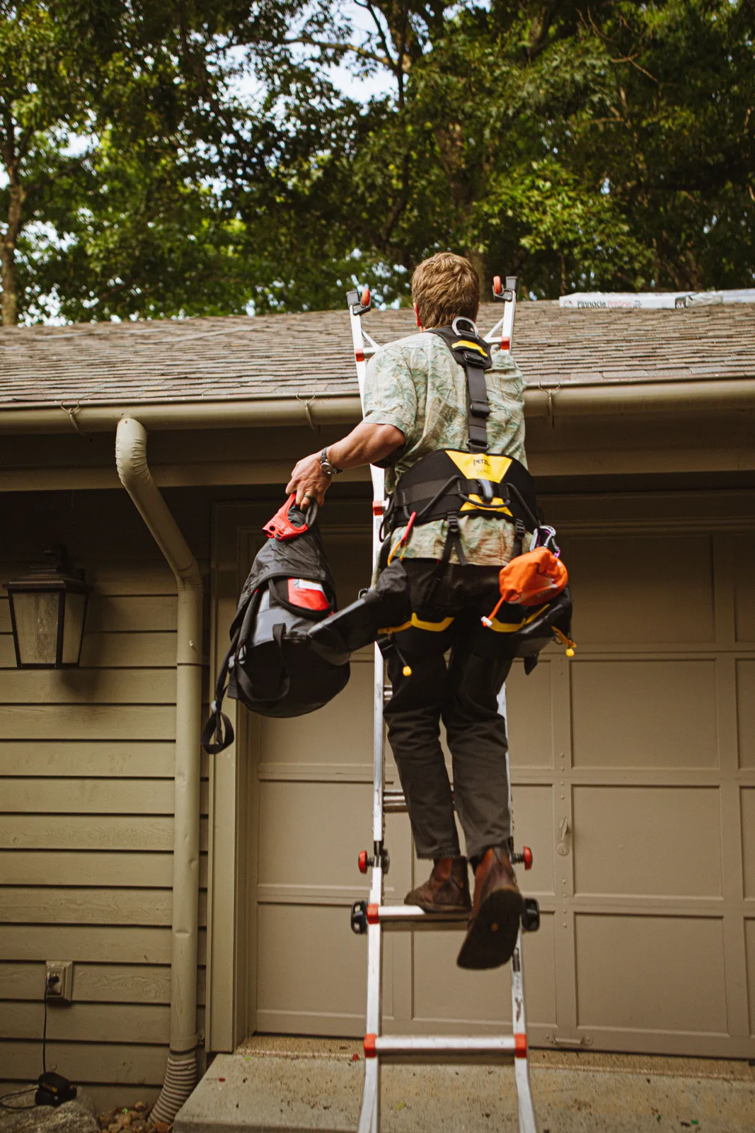 Installer working on a ladder at a roofline